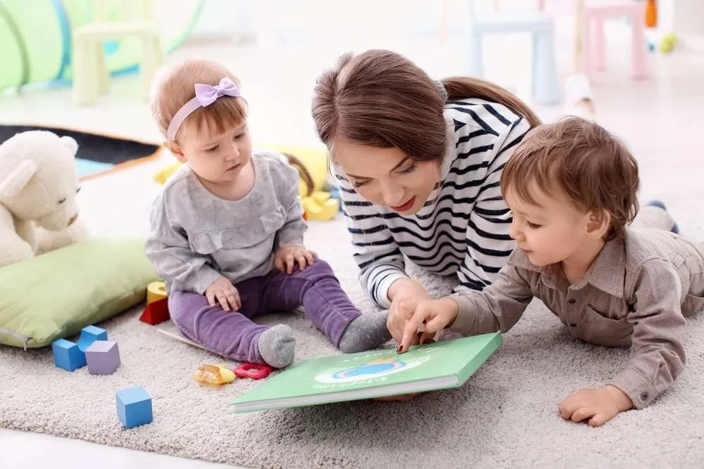 Young nanny with cute little children, indoors