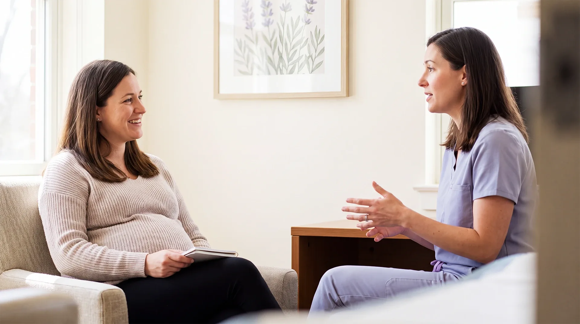 Expectant mother talking with her OB-GYN in a bright consultation room during a first prenatal appointment.