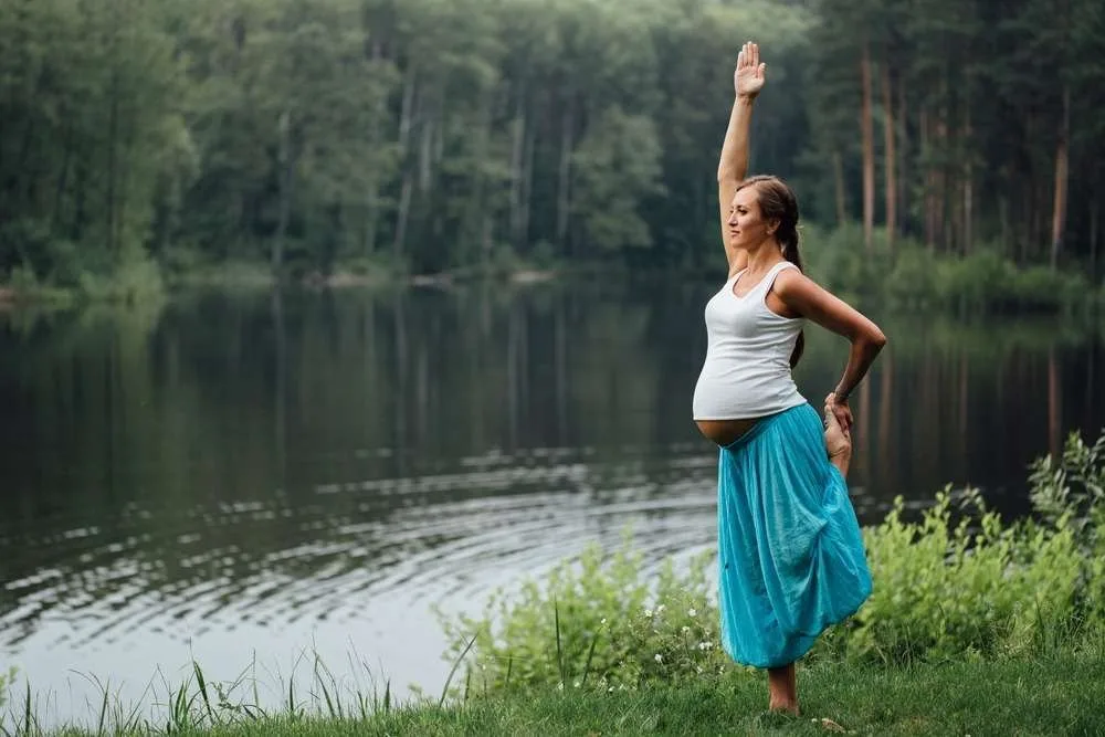 pregnant yoga prenatal maternity doing different exercises. in the park on the grass, breathing, stretching, statics.